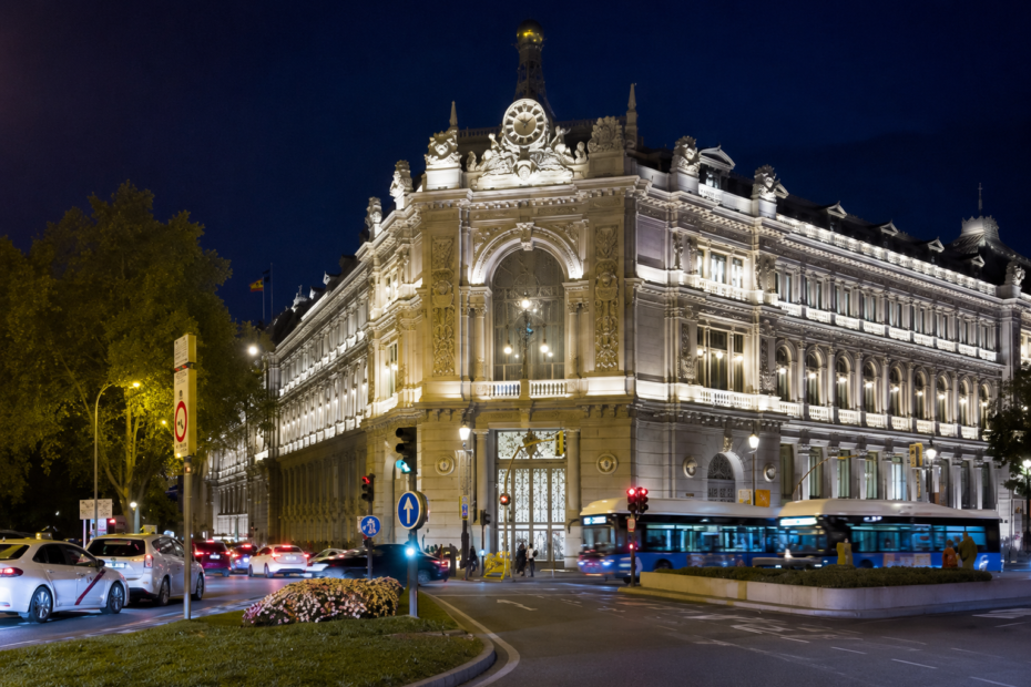 Vista nocturna del edificio del Banco de España en Madrid, relacionado con las nuevas previsiones de inflación y la advertencia sobre el déficit de viviendas en España.